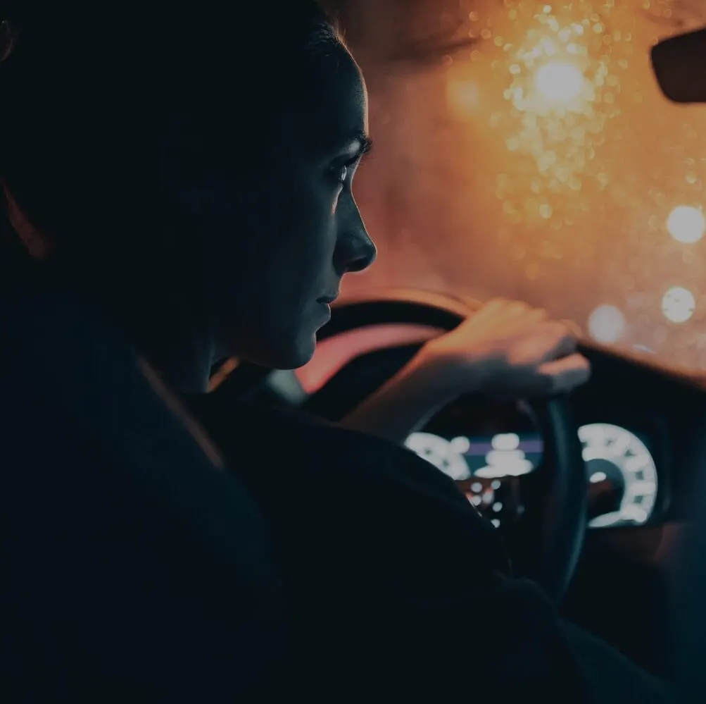 Woman driving at night through rain in Toronto, a reminder of how a DUI conviction can affect car insurance